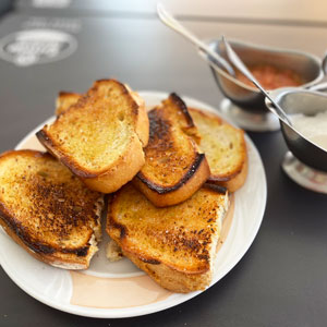 Plato con pan tostado acompañado de all-i-oli y tomate natural rallado, listo para untar, sobre una mesa de restaurante.