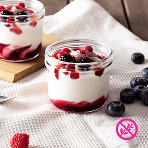 Postre helado de frutas del bosque sin gluten, con base cremosa y coulis de frutos rojos
