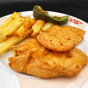 Escalope de pollo empanado servido con patatas fritas y pimiento verde, en plato blanco.