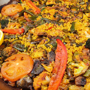 Paella de verduras con arroz seco, cocinada en fogón especial, con pimiento rojo, tomate, brócoli, calabacín, berenjena y otras hortalizas.