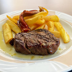 Solomillo de ternera gallega a la brasa con patatas fritas y pimientos verdes.