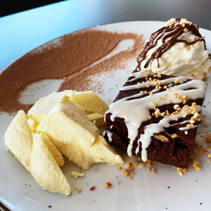 Brownie de chocolate con nueces, helado de vainilla, nata y sirope de chocolate blanco
