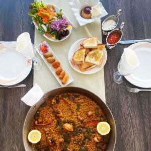 Menú Sabores de la Tierra con paella de carne y verduras, ensalada fresca, entrantes variados, pan tostado y postre casero