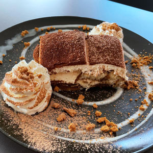 Tiramisú con cacao espolvoreado, nata montada y crocanti