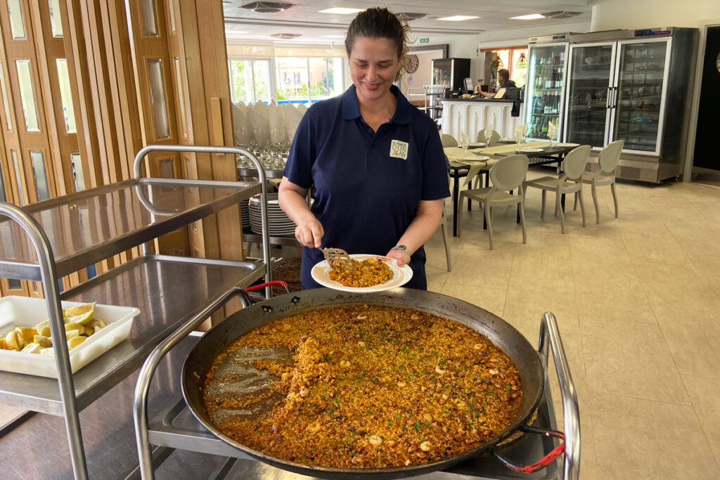 Jefa del restaurante El Algar de Don Joan sirviendo una paella recién hecha, cocina familiar de arroces en las Fuentes del Algar, Callosa d’en Sarrià.